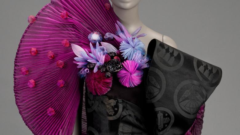 Close-up of a dress that is bright purple and fanned out on one side and black and closely cropped on the other side.