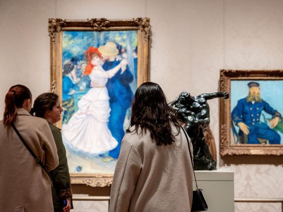 Visitors standing in front of large Renoir painting depicting dancing couple