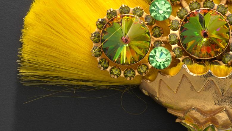 Close-up of a brooch that looks like a yellow flower.