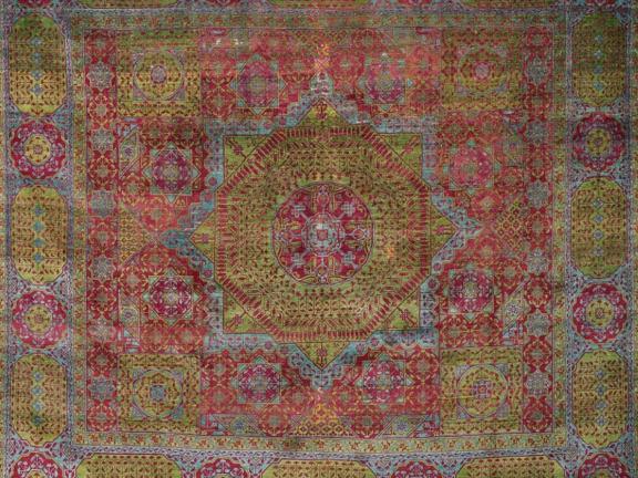 A woven wool carpet made from red, yellow-green, and blue pile yarns and detailed with geometric shapes.