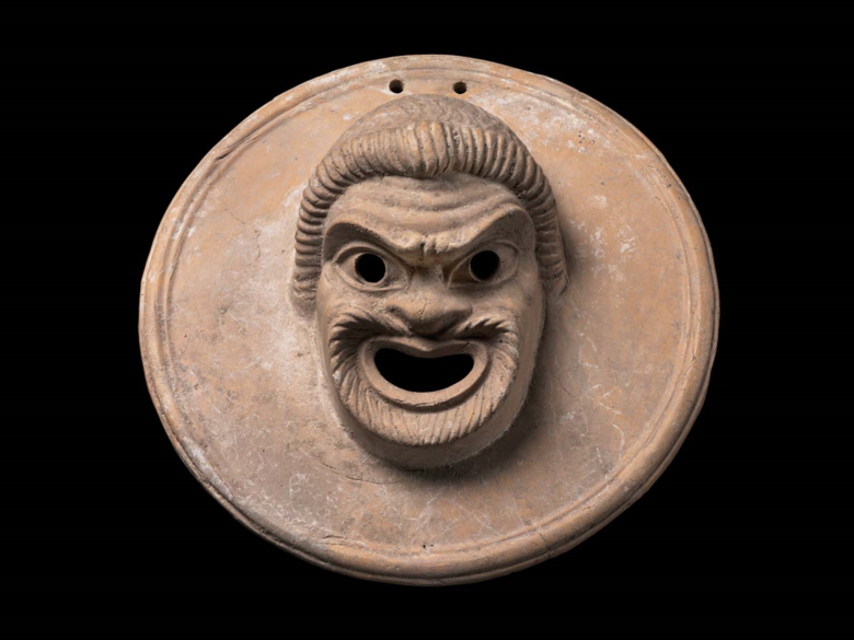 Greek Terracotta suspension disk with an image of a comic mask of a slave