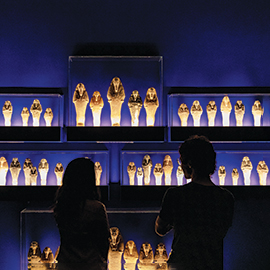 Two visitors looking at display of shawabties in in Ancient Nubia Now exhibition