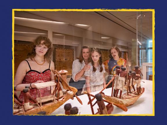 Four visitors in an Egyptian art gallery looking at wooden ship models