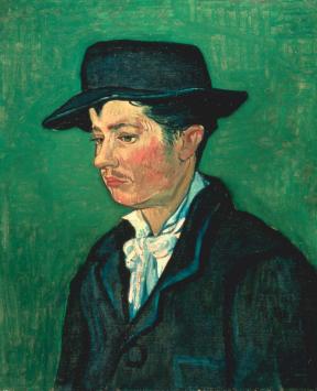 Profile of a man in a yellow jacket, black waistcoat, a tie and a black fedora hat.