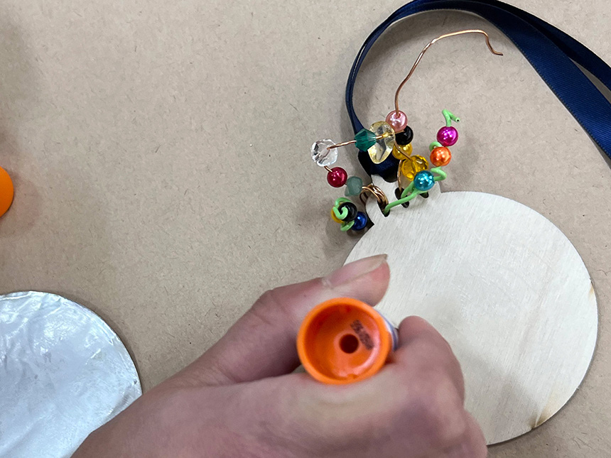 Using glue stick to apply glue to the back of pendant