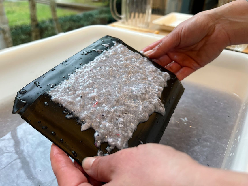 holding the mould flat to allow water to drain from the paper pulp