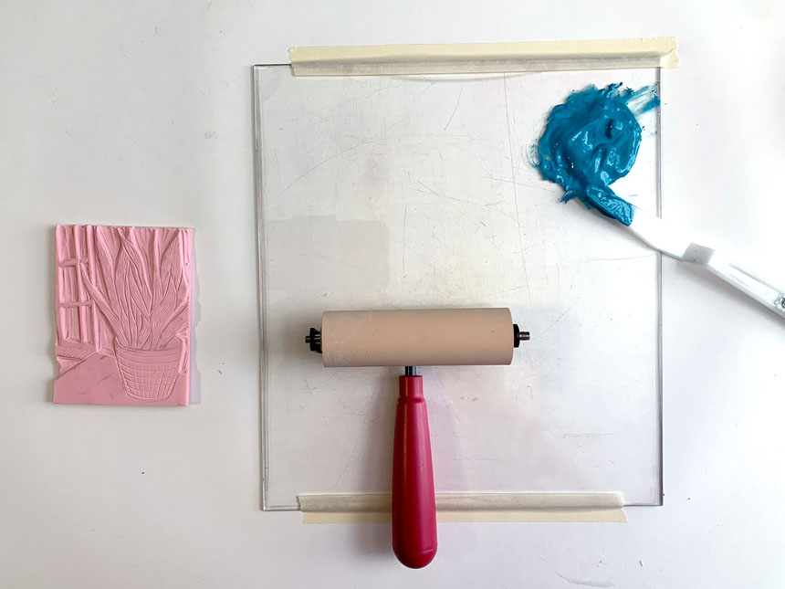 relief block next to plexiglass with brayer, palette knife, and splotch of blue paint on top