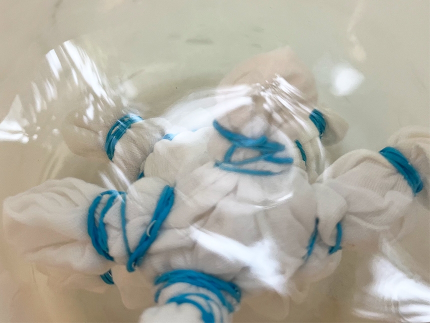 bundle of white cloth tied with rubber bands soaking in water