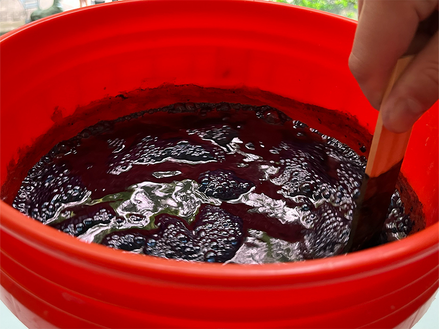 using wooden paint stirrer to mix dye mixture in bucket