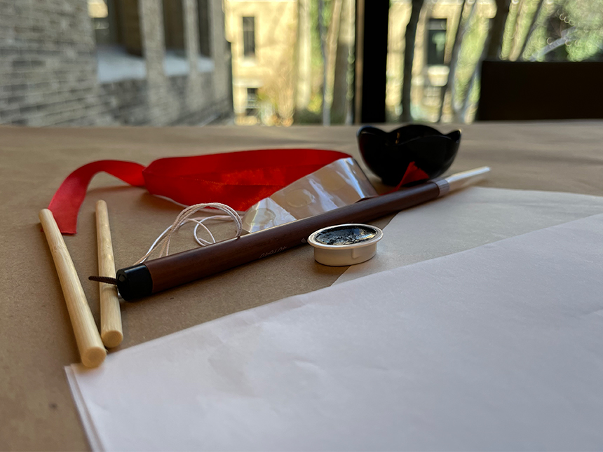 arrangement of various tools and materials, including ink brush, rice paper, two dowels, and ink block