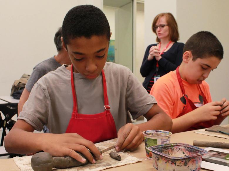 Kids in aprons sculpting with clay at table