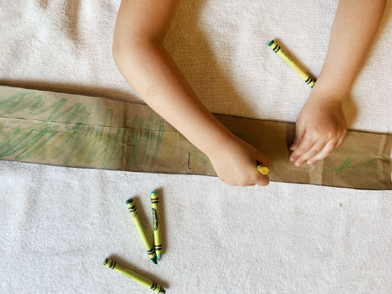 Using crayons and markers to color paper strip