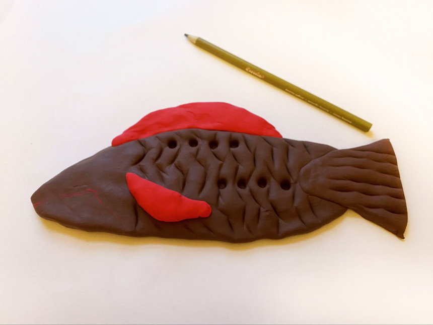 holes made onto clay fish body with pencil