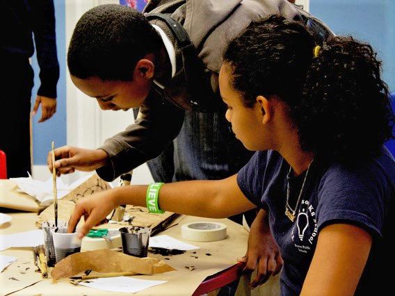 Two teenagers painting with black ink. 