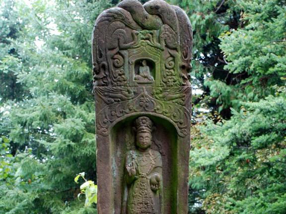 A detail of an ornate stele with a figure carved into the middle. 
