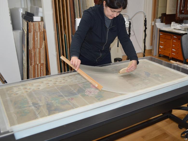 Conservator brushing the facing layer onto a Japanese painting