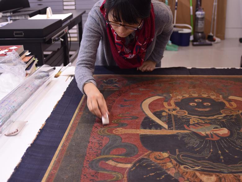 Conservator cleaning surface of a Tibetan painting