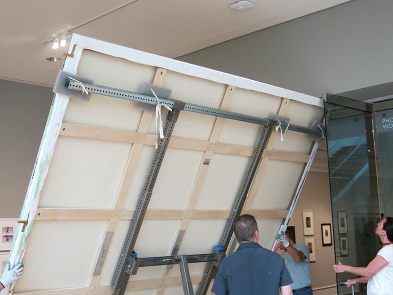 Collections care staff move an oversized painting on a custom-built truck
