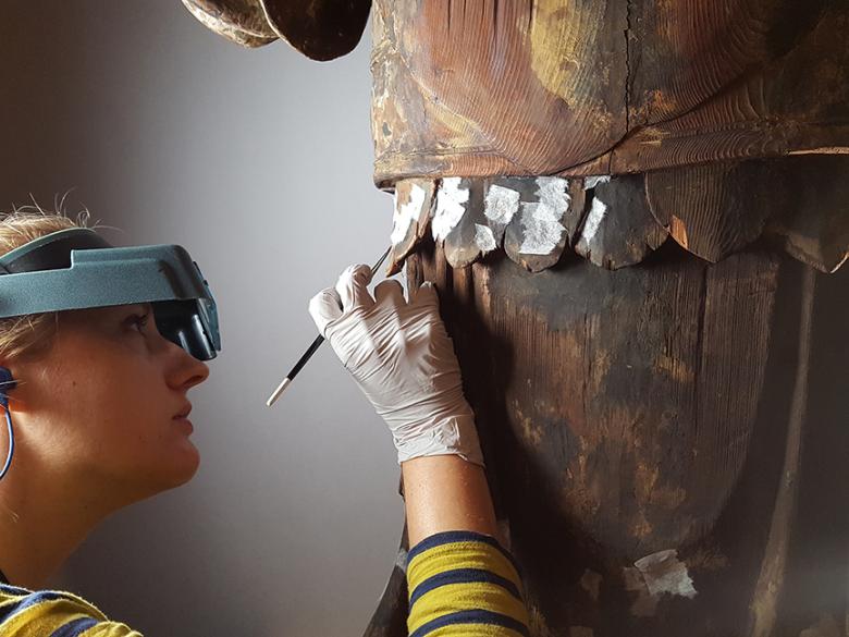 Conservator consolidating pigment on a woodblock construction sculpture