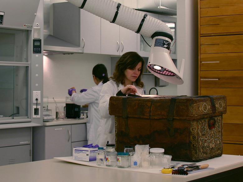 Conservator treating an embroidered trunk