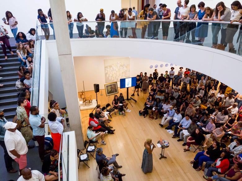 City Talk event taking place in Linde Family Wing; view from second floor, overlooking speaker and audience on first floor; more visitors lining the edge of second floor overlook