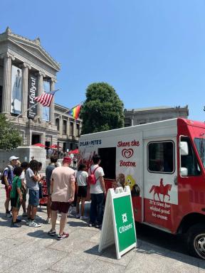 Citizens logo on sandwich sign in front of ice cream truck distributing treats to line of visitors outside Museum's Huntington Avenue Entrance
