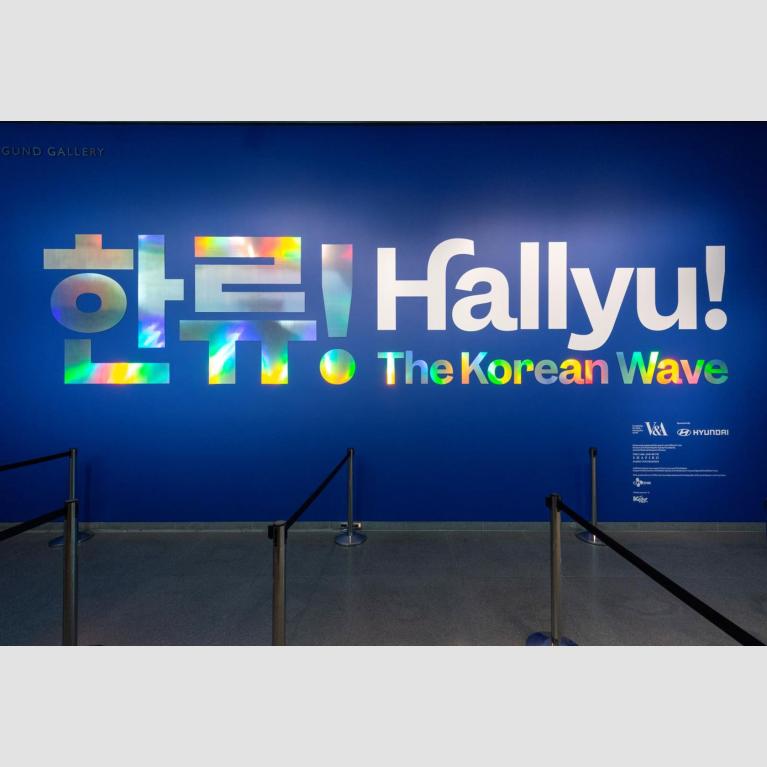 "Hallyu! The Korean Wave" in large metallic letters and Korean characters on wall at exhibition entrance