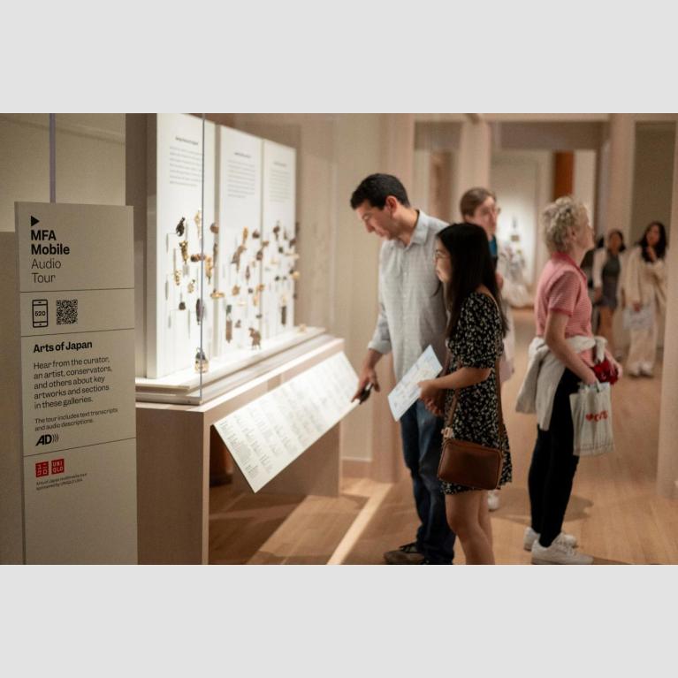 Visitors in Art of Japan gallery looking at various netsuke displayed in tall glass case