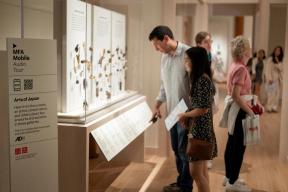 Visitors in Art of Japan gallery looking at various netsuke displayed in tall glass case