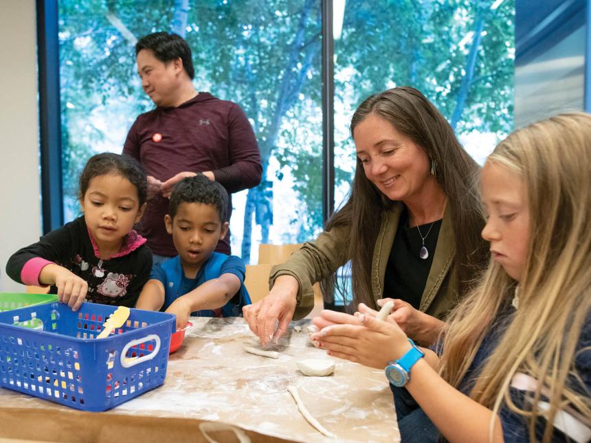 Children and parents working on clay art project while seated at table