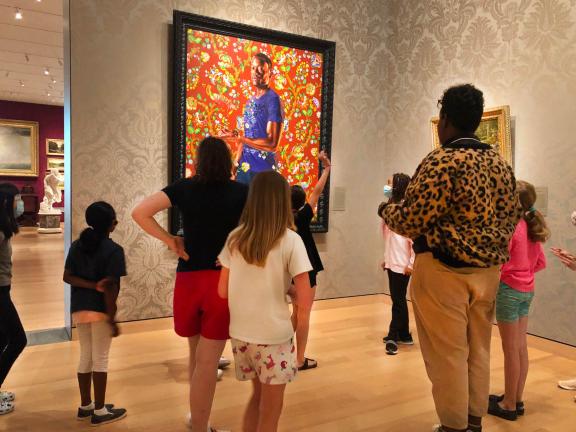 Guide leads discussion with school group of young visitors in front of Kehinde Wiley painting