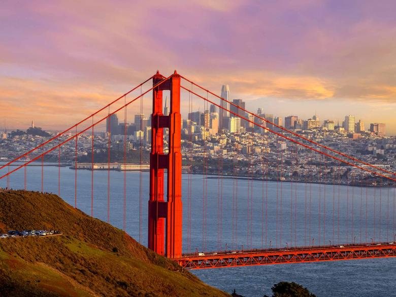 View of Golden Gate Bridge at sunrise with San Francisco in the distance