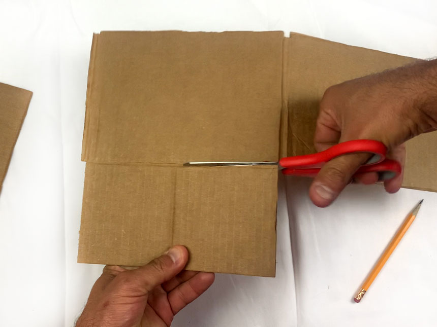 using scissors to cut flaps off cardboard box