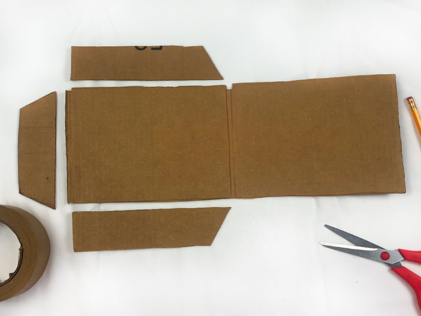 two sides of cardboard box laid out on table with three smaller trapezoid pieces positioned to the top, bottom and left of bigger piece