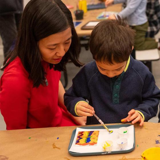 A woman and child sit at a table and paint.
