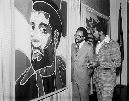 Two men stand in front of a painting.