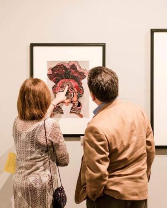 Two visitors looking at art hanging on gallery wall