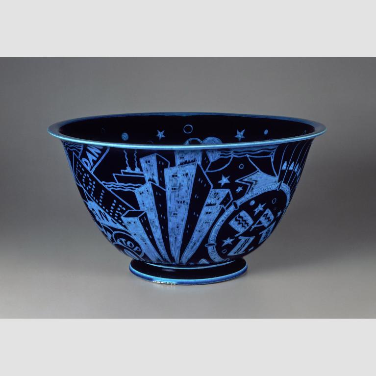 A glazed, black porcelain bowl is decorated with brilliant blue incised motifs of New York City attractions