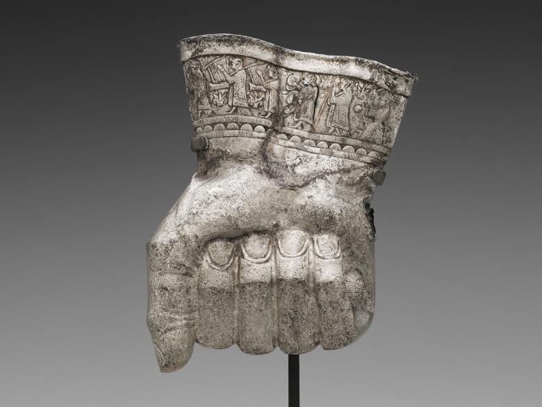 metal sculpture depicting closed fist with musicians etched around wrist