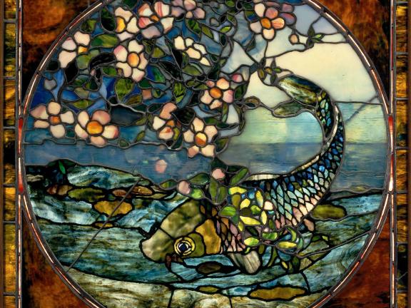 A leaded and stained glass image of a fish wrapped in pink flowers. 