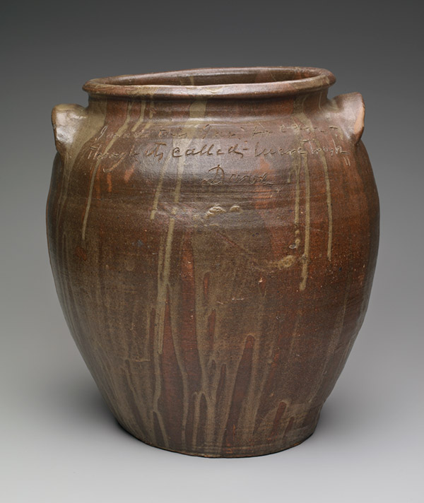 A brown clay pot with a lip, two handles, and dripped in a lighter glaze. 
