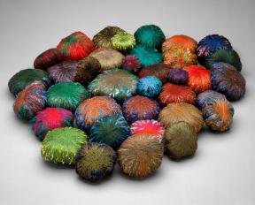 Thirty-six wrapped bundles of polychrome yarns wound around miscellaneous objects.