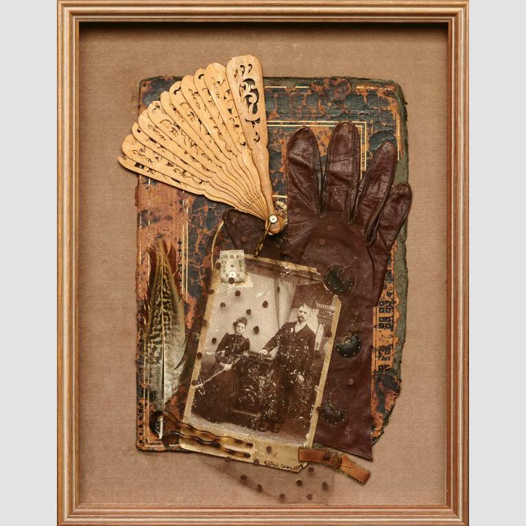 A framed mixed media artwork of a Victorian photograph covered in lace, a leather glove, and an aged fan.