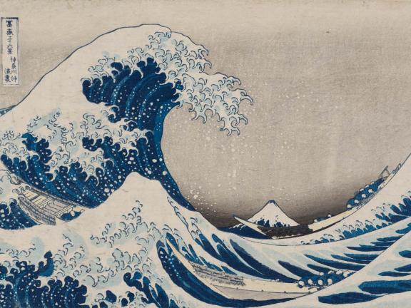 A bright blue tidal wave crests on choppy waters with a mountainscape in the distance.