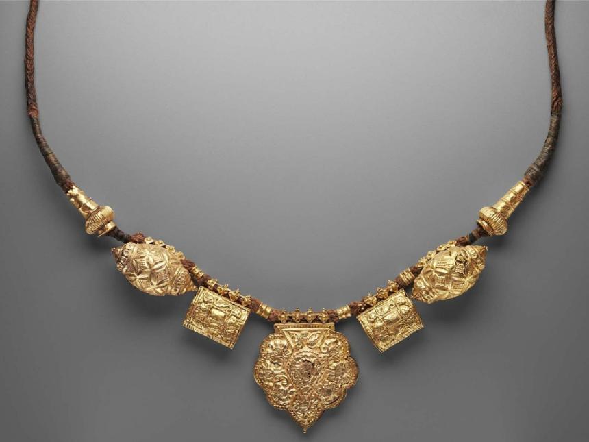 gold necklace with several pendants on a brown cord