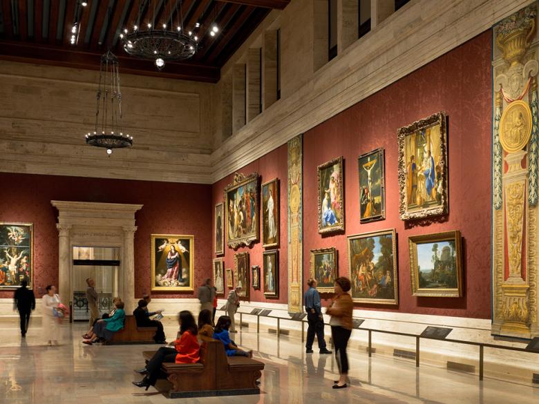 View of gallery with large European paintings and tapestries on walls