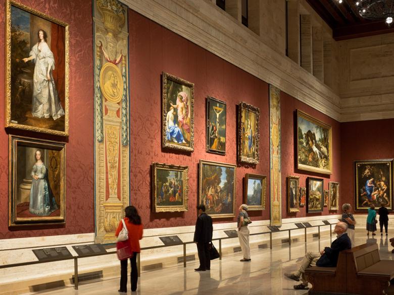 View of gallery with large European paintings and tapestries on walls