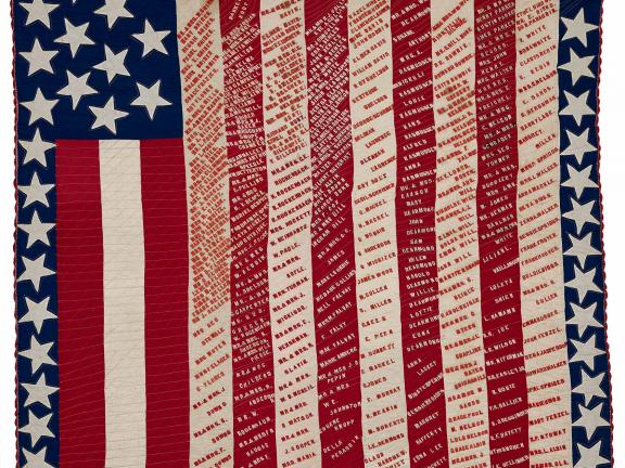 Red, white and blue quilt with stars, stripes and text