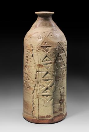 A light tan, cylindrical stone vessel with a tapered opening and varied carvings.