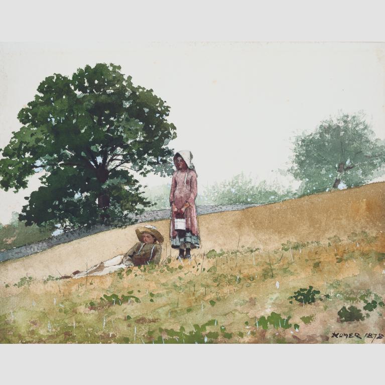 A boy lies in a field while a girl stands next to him.